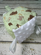 Load image into Gallery viewer, A handmade sensory baby toy cube with a light green fabric printed with brown bears, a white minky dot fabric panel, and white ribbon loops, displayed on a rustic white-washed wooden surface.
