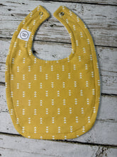 Load image into Gallery viewer, baby bib gold yellow with a small white arrow motif.
