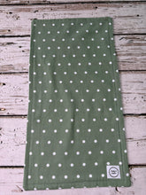 Load image into Gallery viewer, An olive green fabric cloth with a white polka dot pattern, laid flat on a rustic white-painted wooden surface. 
