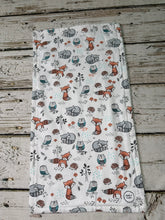 Load image into Gallery viewer, A rectangular white burp cloth featuring a whimsical woodland animal print of foxes, owls, hedgehogs, and pinecones. The fabric is laid flat on a rustic, weathered gray wooden plank surface.
