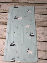 Load image into Gallery viewer, A rectangular baby burp cloth, featuring a printed pattern of polar bears, mountains, and trees, laid flat on a rustic wooden plank background.
